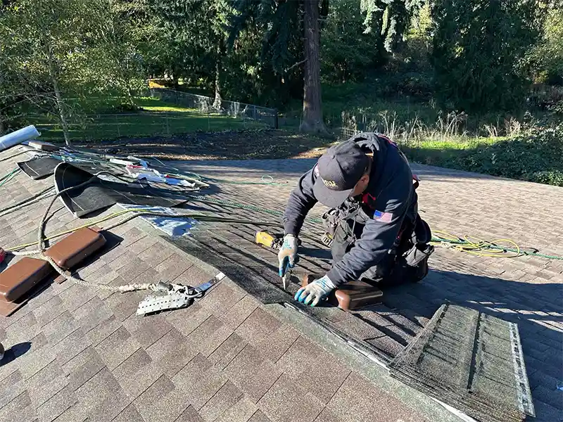 Crew member installing new shingles on a roof